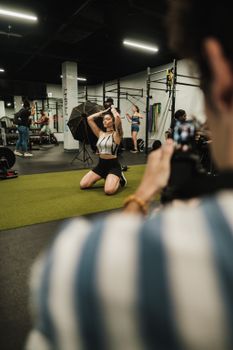 Dynamic fitness photoshoot with a kneeling model in activewear, indoor gym