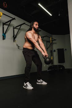 Bearded man swinging kettlebell in modern gym, showcasing strength and fitness.