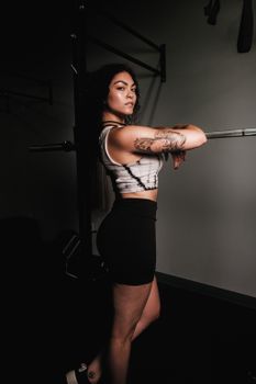 Woman with tattoos posing confidently in gym. Strong and athletic vibe.