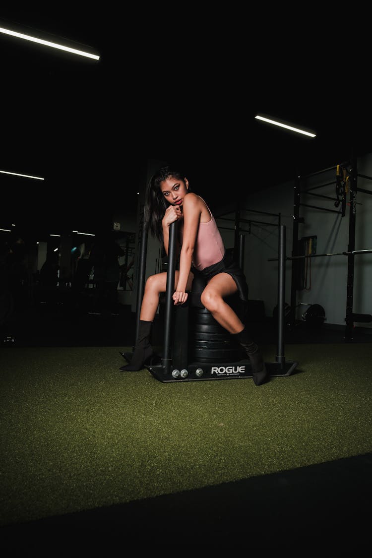 Woman Sitting On Weights In A Gym