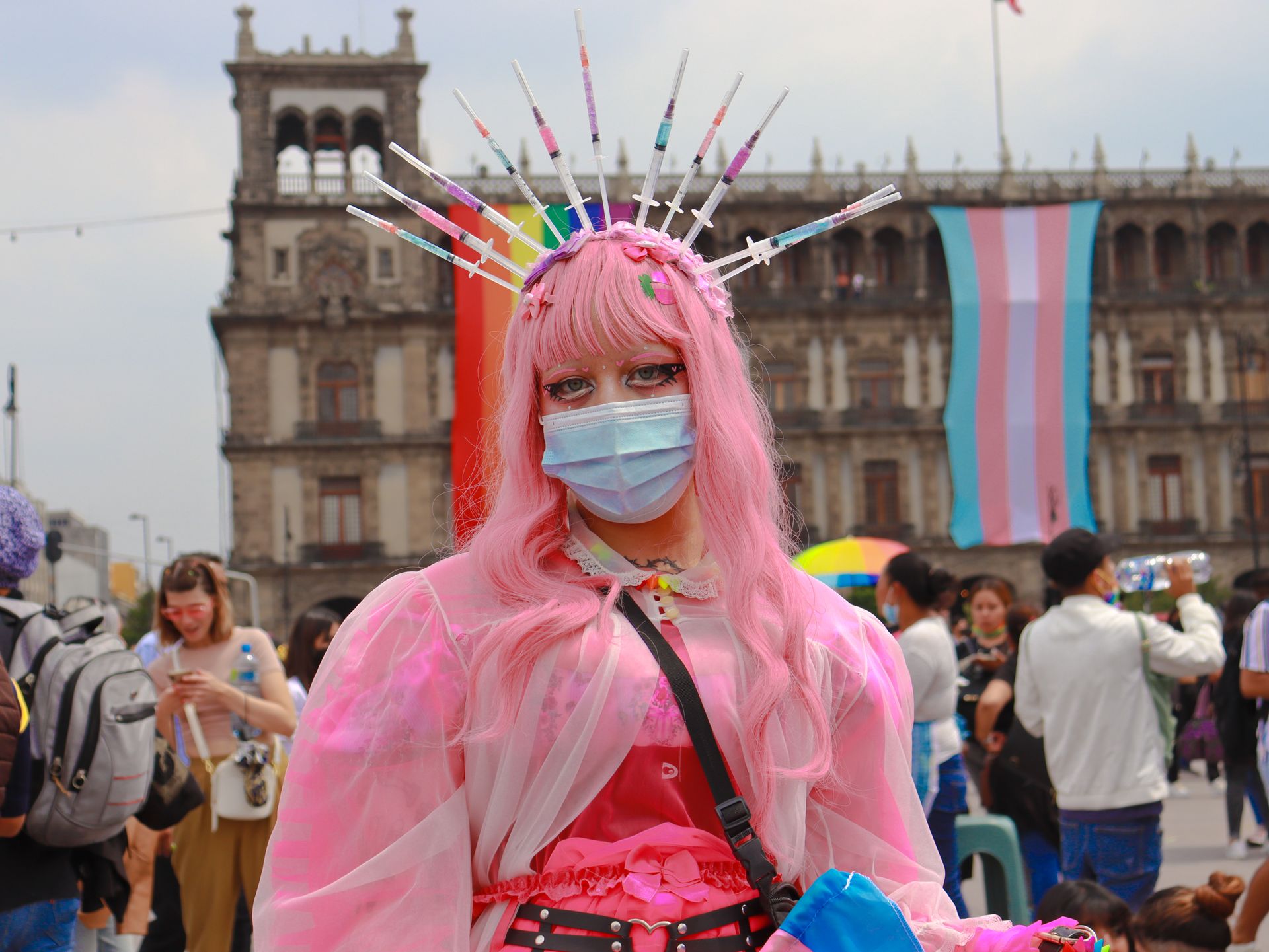 A colorful Pride event showcasing a costumed participant with vibrant LGBTQ+ flags in the background.