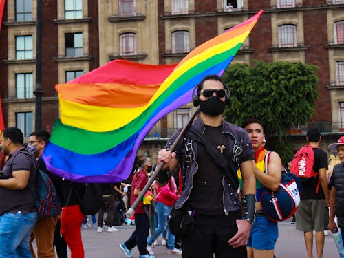 Man in Black Shirt Holding Rainbow Flag