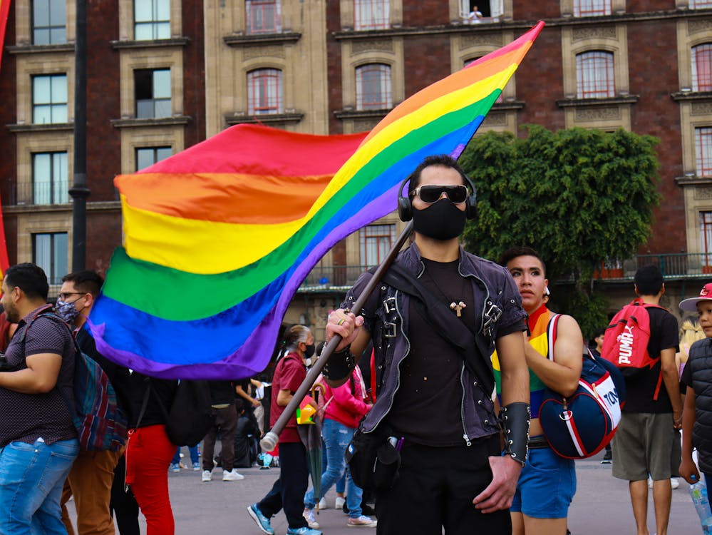 Man in Black Shirt Holding Rainbow Flag