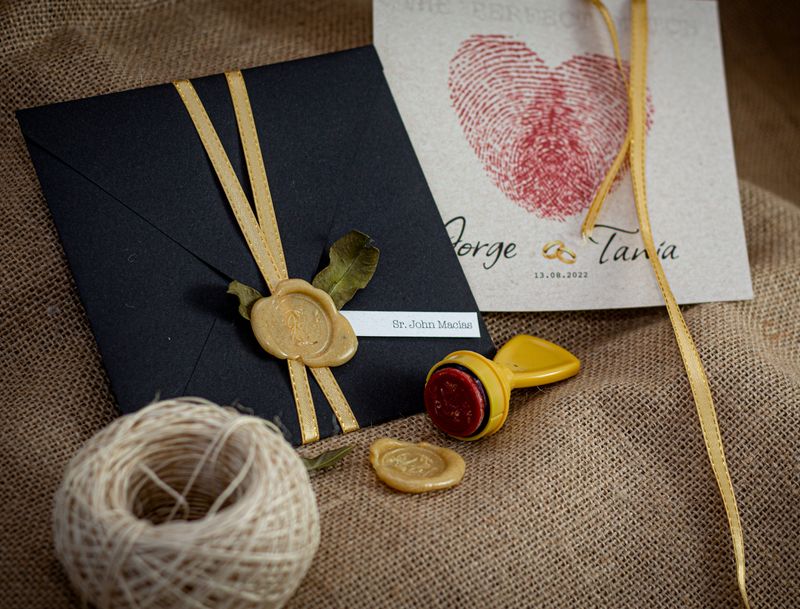 Black envelope tied with gold ribbon and wax stamp detail