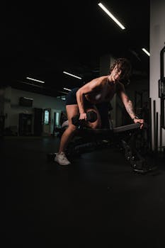 A determined woman working out with a dumbbell in a modern gym, showcasing fitness strength.