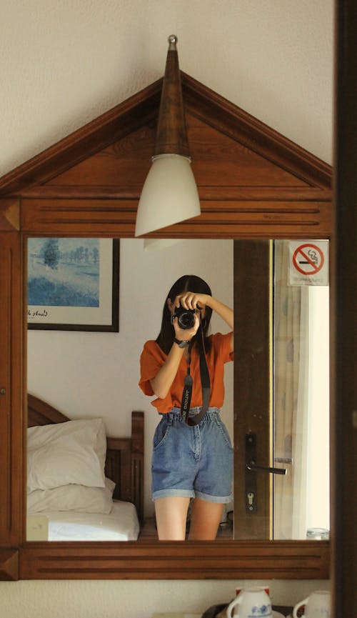 Woman in Denim Shorts Using a Camera