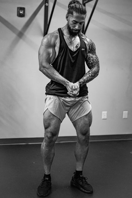 Muscular man flexing in a monochrome gym setting, showcasing tattoos and strength. Muscular man flexing in a monochrome gym setting, showcasing tattoos and strength.