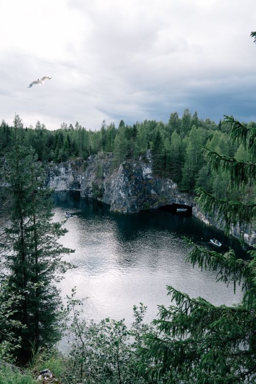 Free A beautiful view of a serene lake surrounded by cliffs and dense forest, perfect for nature travel. Stock Photo