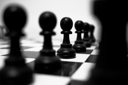 Black and white chess pawns aligned on a checkerboard, symbolizing strategy and planning.