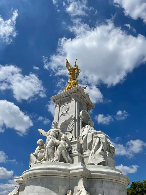 Free Stunning low-angle shot of the Victoria Memorial set against a bright, cloud-filled sky in London. Stock Photo