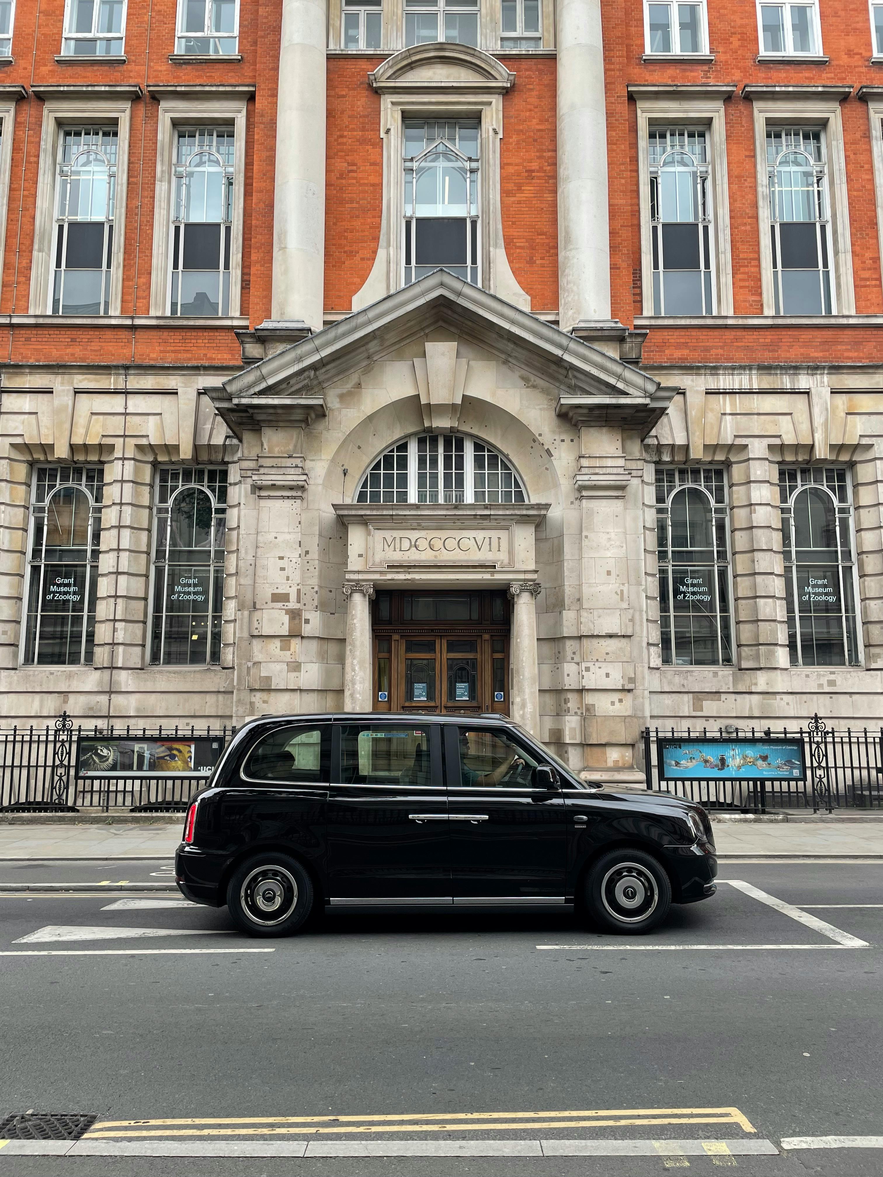 black car on the road near concrete building with glass windows