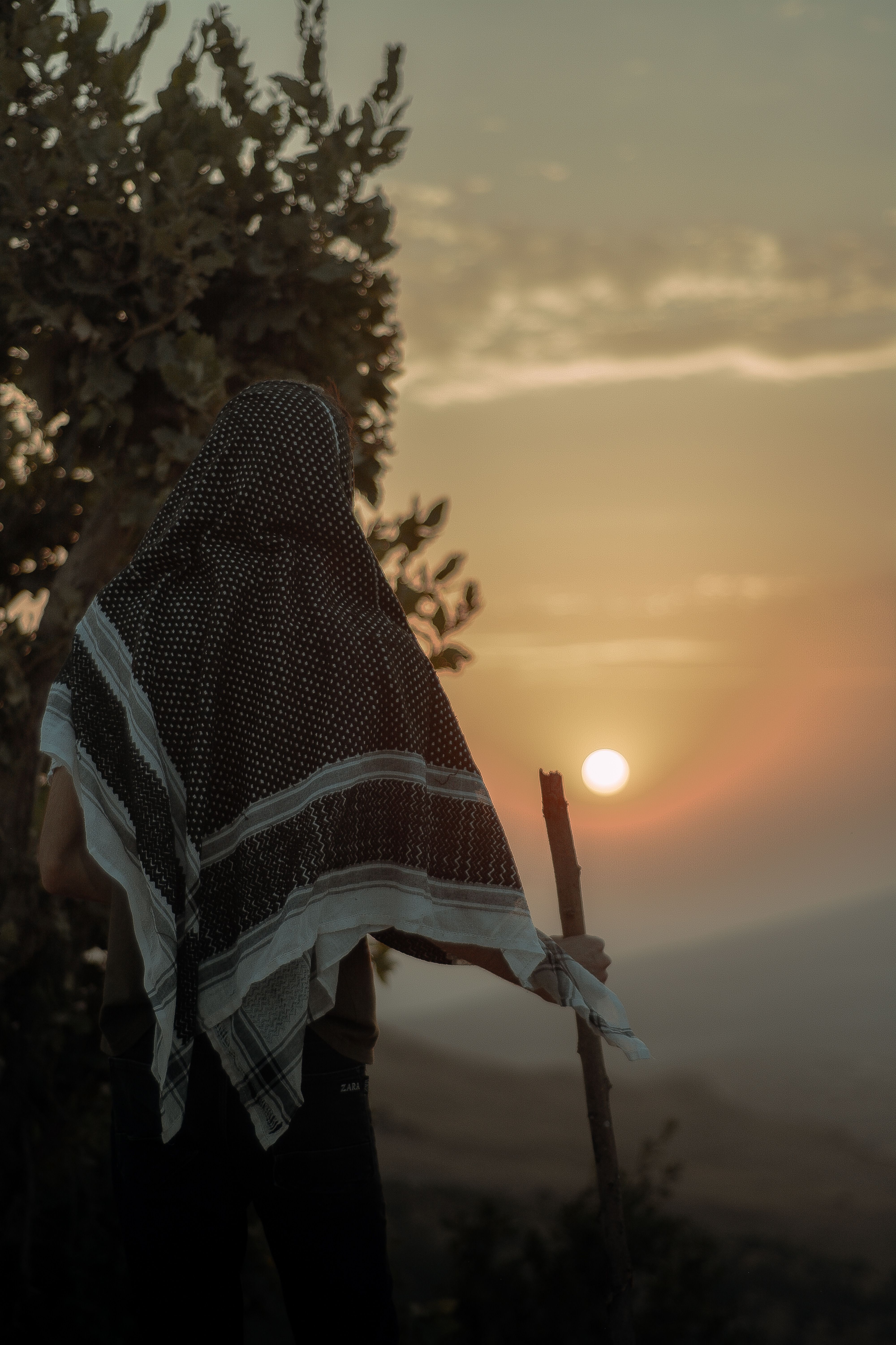 Silhouette of a person with headscarf and walking stick watching the sunset in Erbil, Kurdistan Region, Iraq.