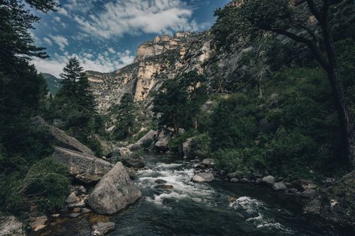 Free Explore the serene beauty of a mountain river flowing through lush greenery and rocky terrain. Stock Photo