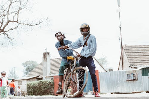 Person Wearing Helmet Holding Bicycle With Man Riding