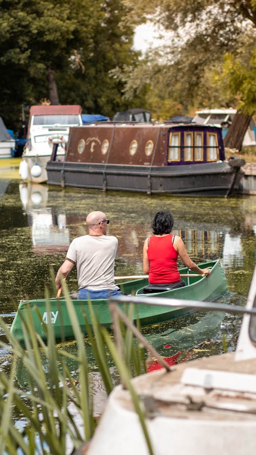 A Couple Riding a Green Boat on Body of Water