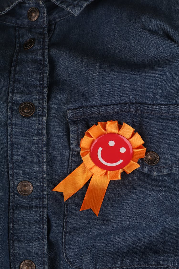 A Smiley Pin On A Denim Shirt