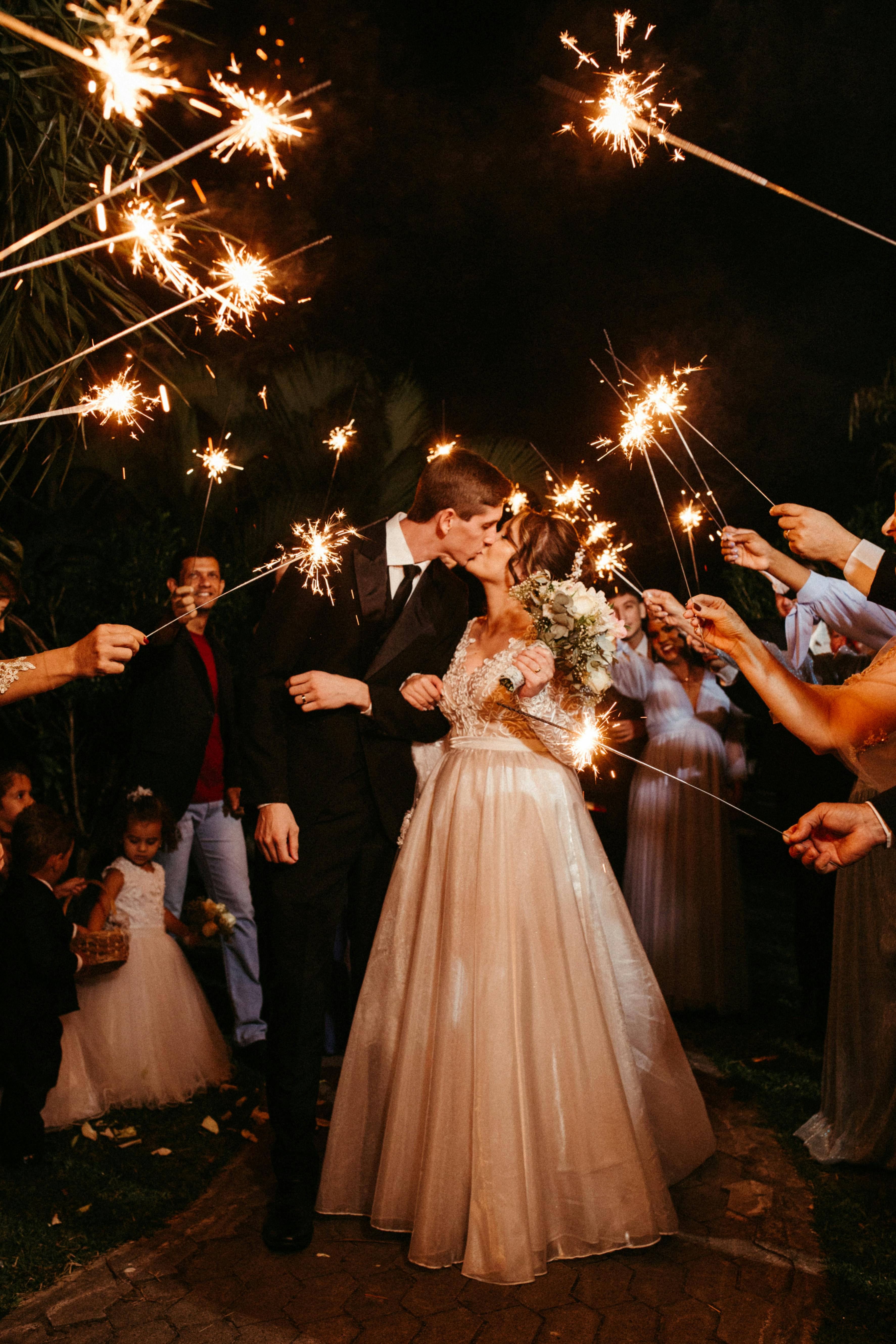 A captivating night scene of newlyweds kissing amidst sparklers, celebrating love and joy.