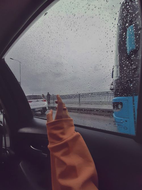 Free View of a rainy street through car window with raindrops creating a moody atmosphere. Stock Photo