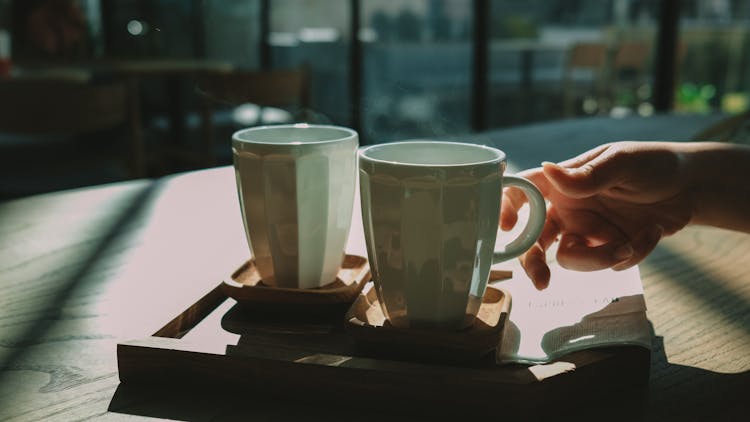 A Person's Hand Grabbing A Cup