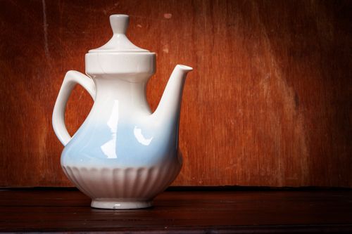 Free A close-up view of a white ceramic teapot set against a rich wooden background, showcasing elegance and simplicity. Stock Photo