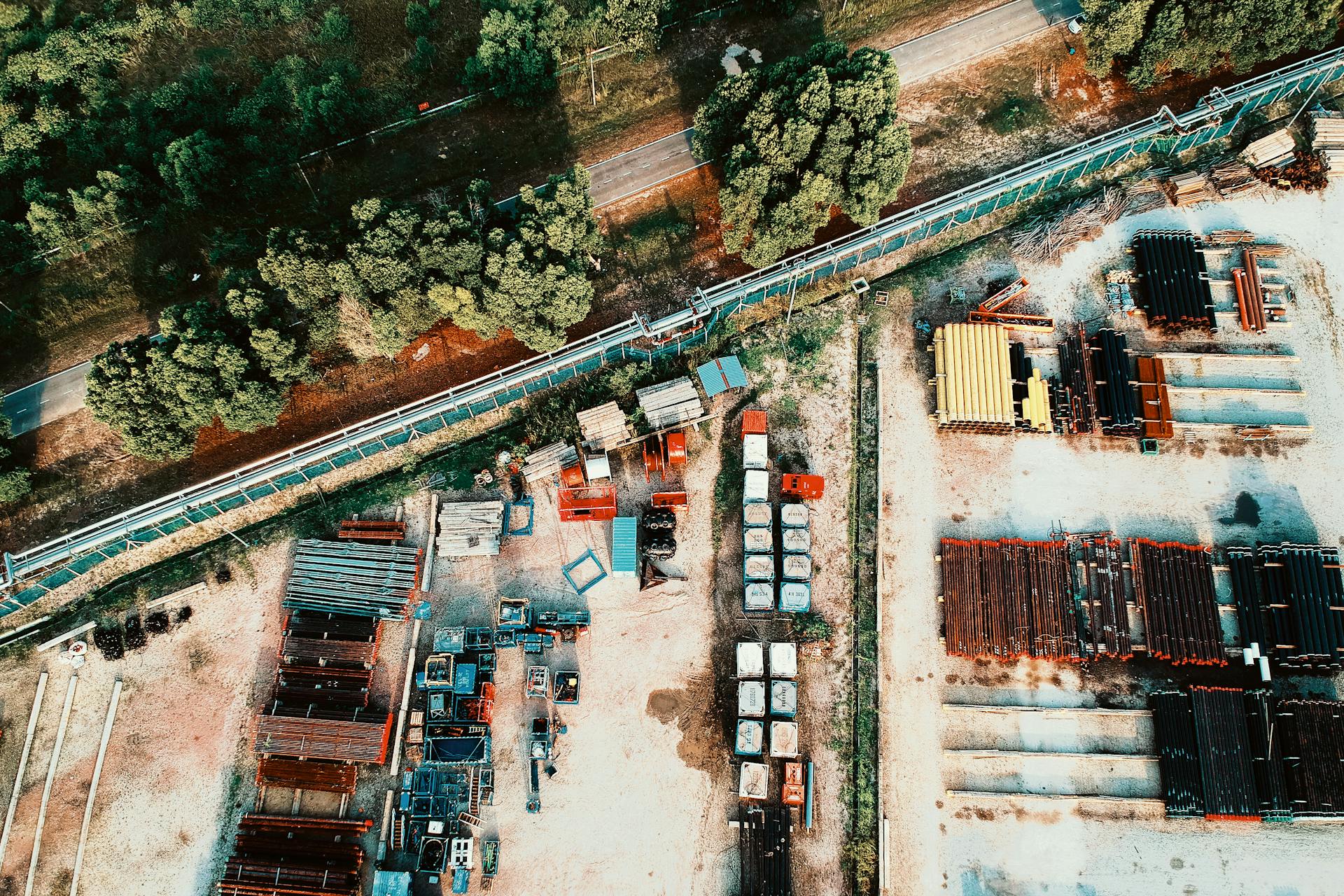 A detailed aerial shot showcasing an outdoor industrial storage facility with metal materials and surrounded by trees.