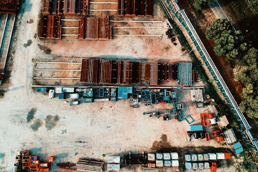 Aerial shot of organized industrial storage yard with steel structures and equipment, surrounded by greenery.