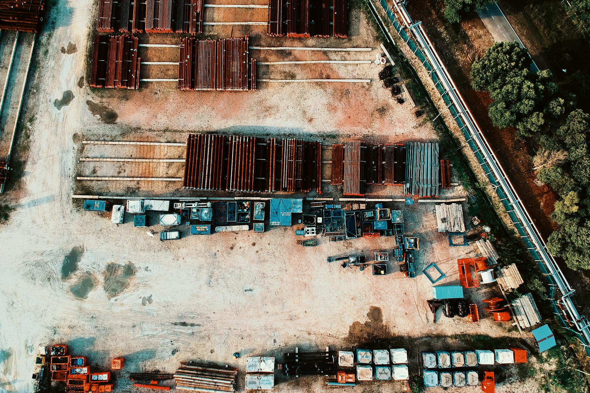 Aerial shot of organized industrial storage yard with steel structures and equipment, surrounded by greenery.