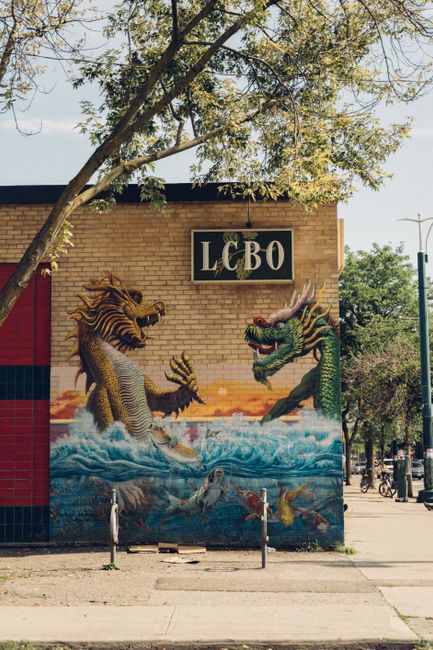 Vibrant dragon mural on a brick LCBO wall with trees and clear sky.