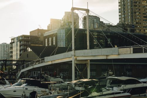 Free A bustling urban marina at sunset showcasing modern architecture and moored yachts. Stock Photo