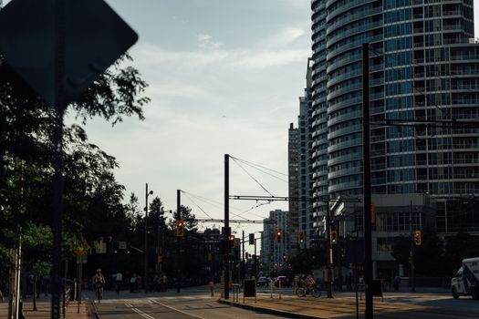 City street scene featuring cyclists, skyscrapers, and urban architecture under evening light.