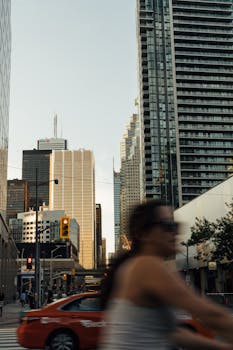 A bustling city street with blurred motion and towering skyscrapers under a soft evening light.
