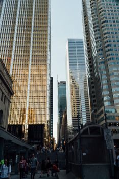 Low angle view of towering skyscrapers reflecting evening light in a bustling city.