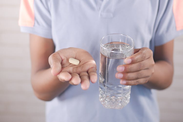 Woman Holding A Pill And A Glass Of Water 