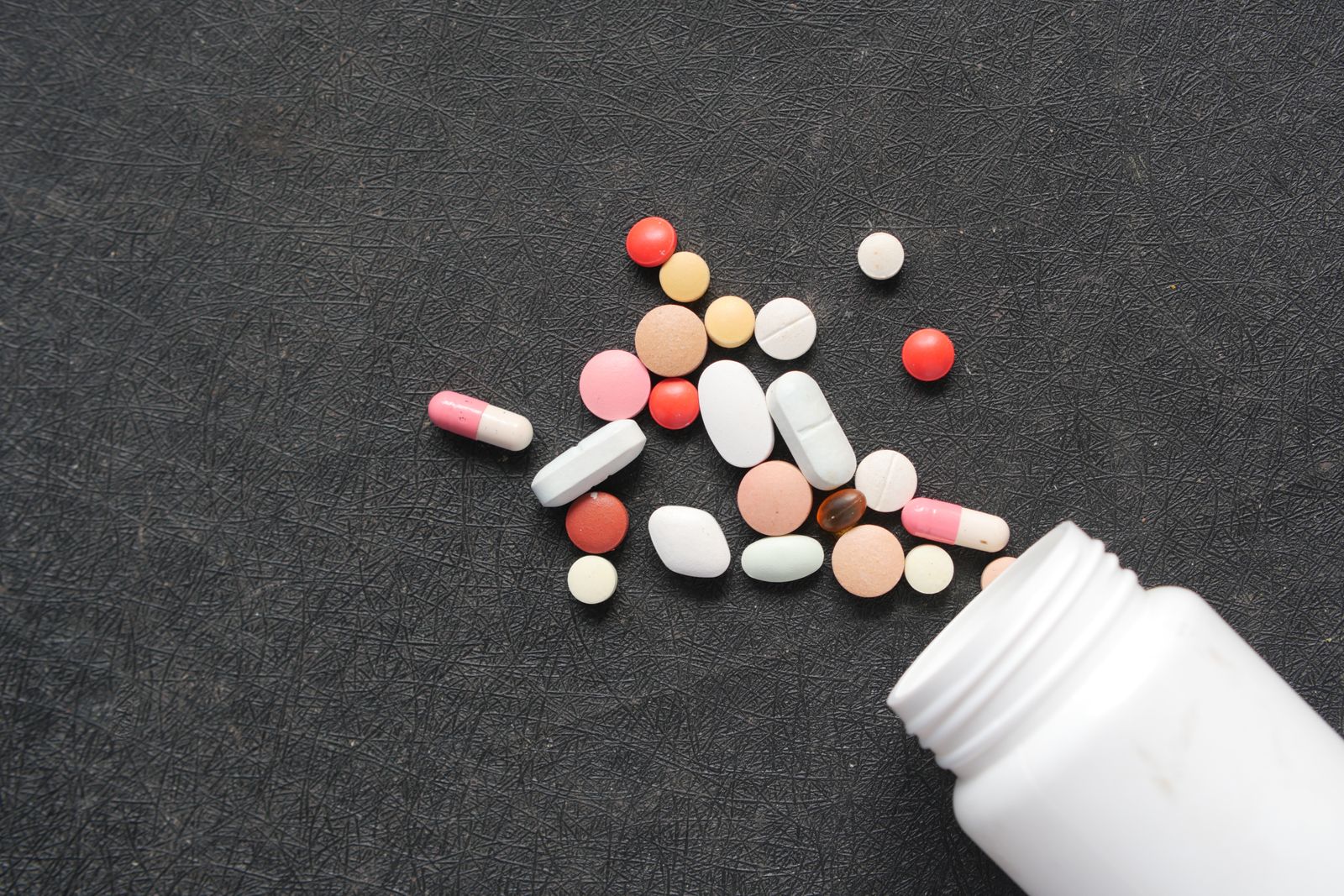 Prescription pills and medication bottle on a dark surface