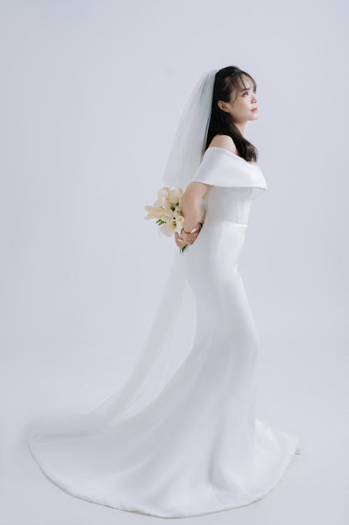 Photo of a Bride in a White Dress Holding a Bridal Bouquet