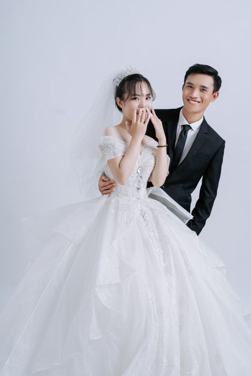 Free A joyful Asian couple in wedding attire posing and smiling for a classic portrait. Stock Photo