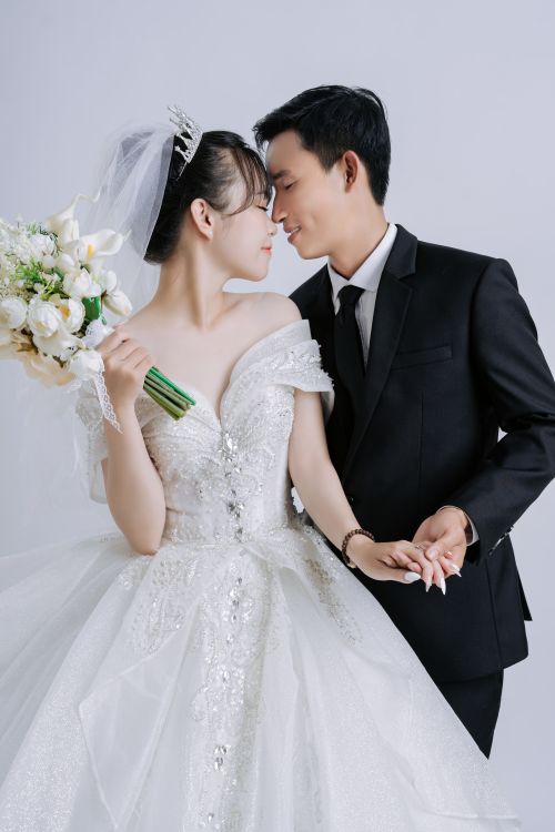 Free Asian couple sharing a tender moment in wedding attire, symbolizing love and union. Stock Photo