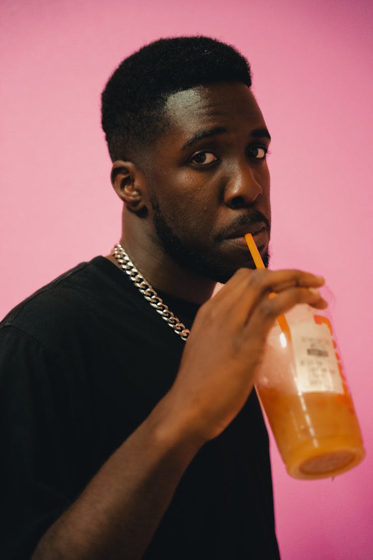Man Drinking Juice On Pink Studio Background