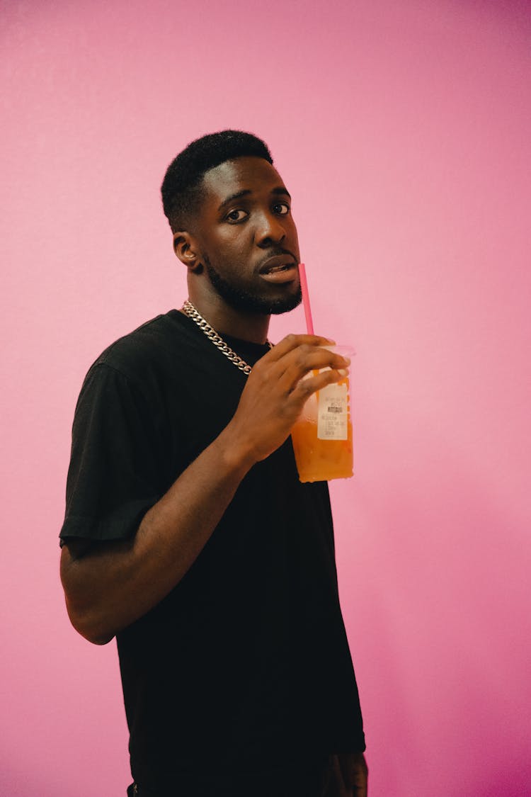 Man Drinking Juice On Pink Background