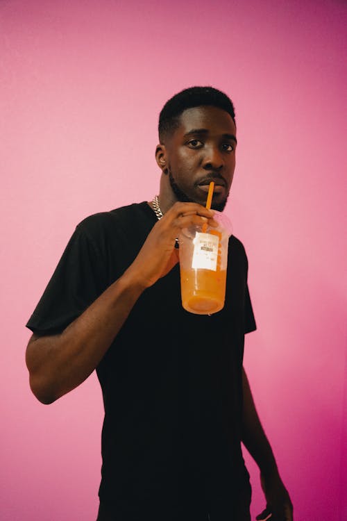 Man in a Black Shirt Drinking from a Plastic Cup