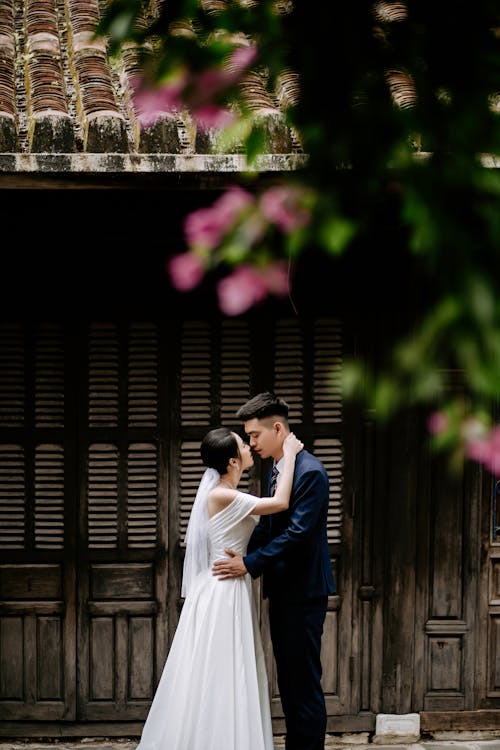 A Couple Kissing Near a Wooden House