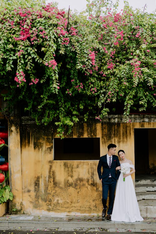 Photo of a Bride and a Groom Near Pink Flowers