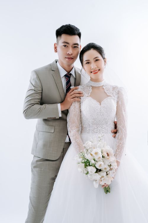 Free Couple in bridal attire posing for a wedding photoshoot against a white background. Stock Photo
