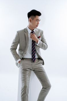 Stylish studio portrait of an Asian man in a suit and tie, exuding confidence.