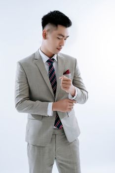 Asian groom posing in a stylish suit for a studio photoshoot, exuding confidence and elegance.