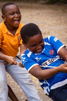 Two African boys enjoy a playful game of tug of war, showcasing joy and friendship.