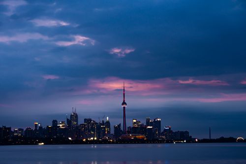Free Dramatic view of Toronto's skyline at sunset, featuring the illuminated CN Tower against a vibrant sky. Stock Photo