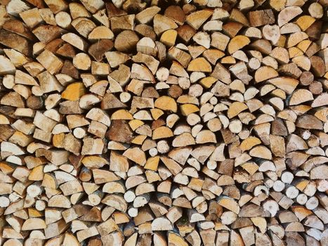 Close-up view of stacked firewood, showcasing rustic texture and pattern in an outdoor setting.
