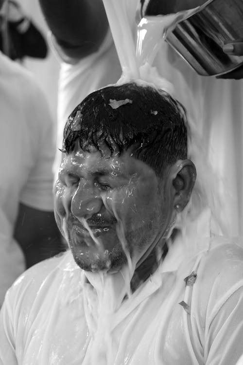 Water and Milk is Poured over a Head of a Man