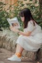 一位穿着连衣裙的亚洲妇女在户外读书，享受着夏日时光